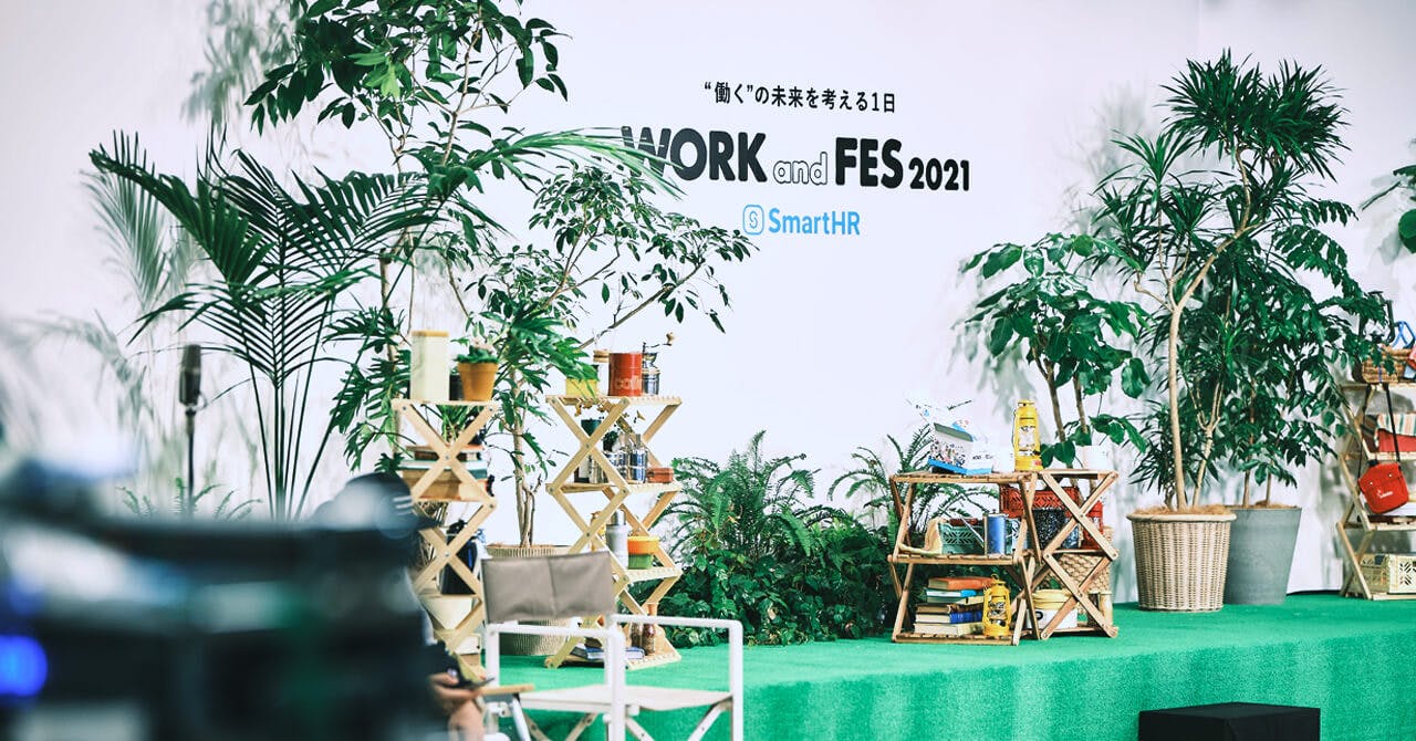 「WORK and FES2021」イベント会場の写真。ステージ上に木々やアウトドアグッズが並べられている。