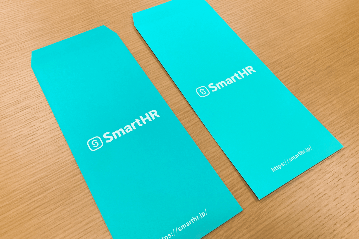 SmartHRのロゴが入った封筒が2つ並んでいる画像。色転びにより、左右で色が異なる。